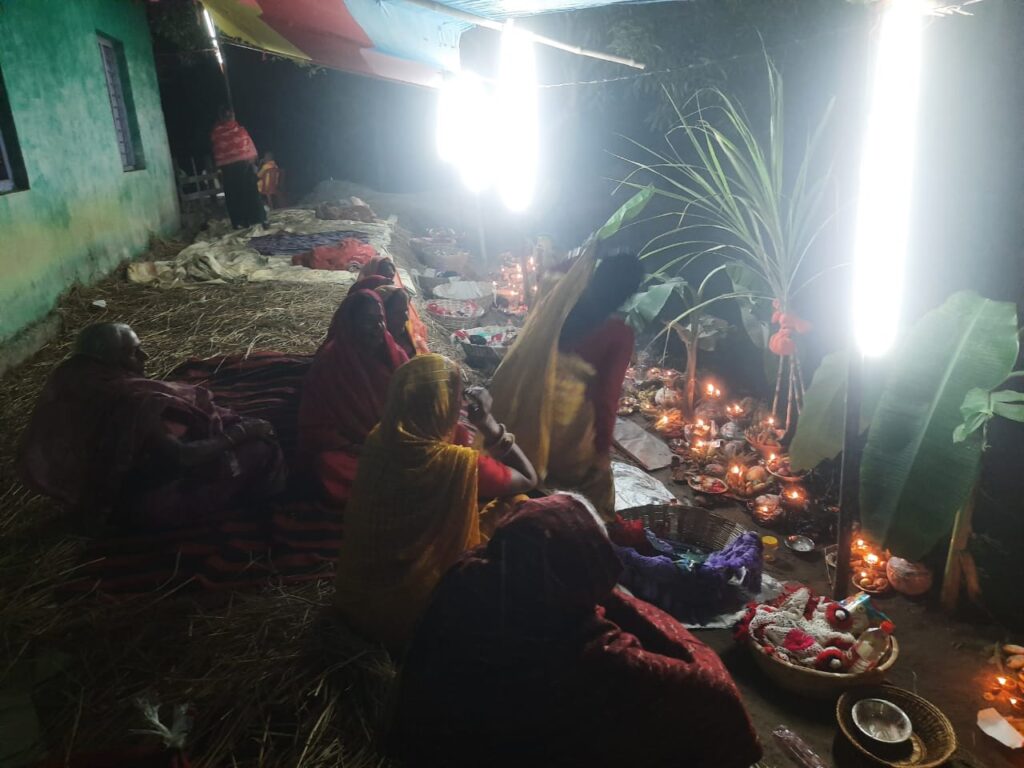 Chhath devotees staying awake throughout the night at the Chhath Ghat and lighting an incense stick, candle, and diya, and singing