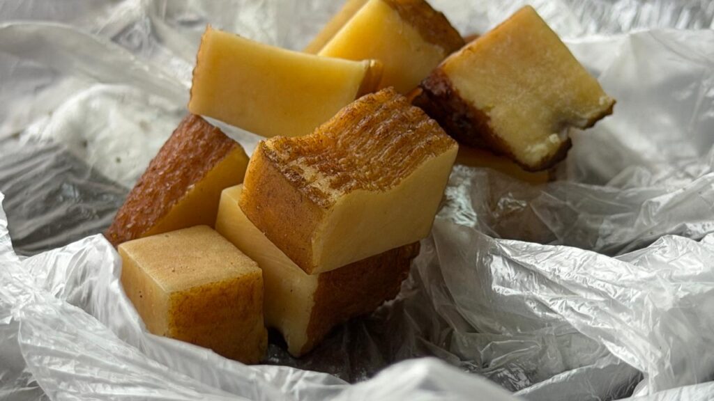 Authentic Himalayan hard cheese (Chhurpi) cubes wrapped in clear plastic, traditional mountain food.